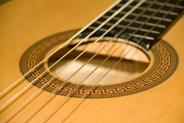 A nylon-string classical guitar resting on a stand, showing its wide flat fretboard and nylon strings