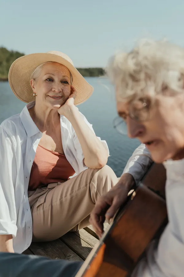 An older adult playing a classical guitar seated comfortably, demonstrating that it's never too late to start learning