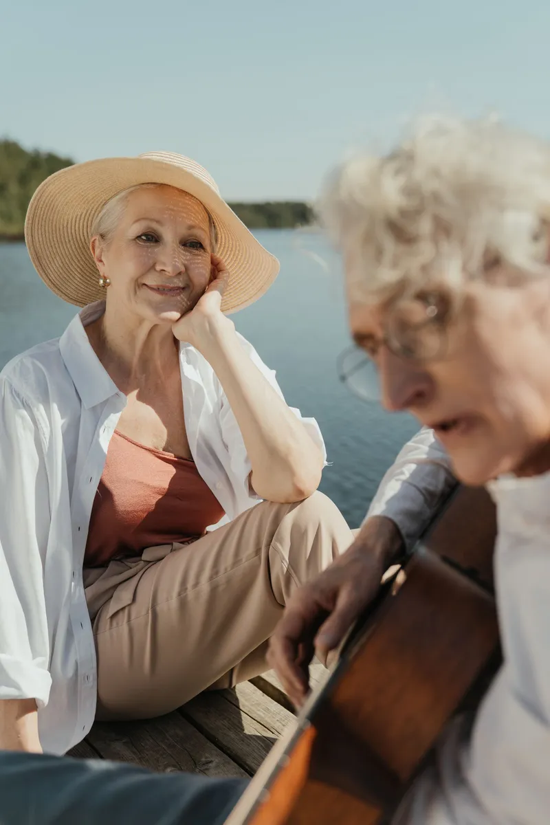 An older adult playing a classical guitar seated comfortably, demonstrating that it's never too late to start learning